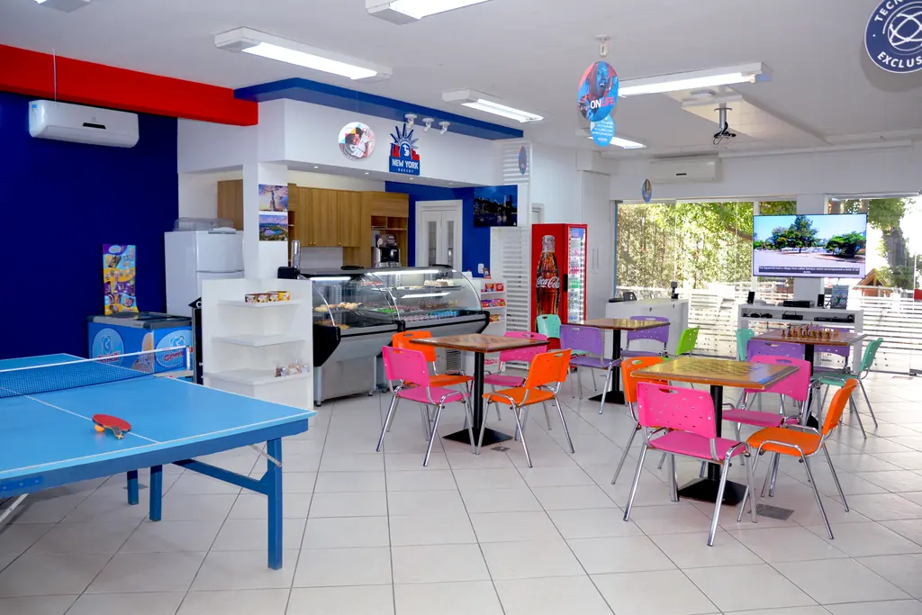 Lanchonete e área de convivência com mesa de pingue-pongue, mesas coloridas e balcão